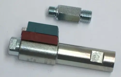 Daikin Ölvorwärmer mit einer zylindrischen Form und zwei Anschlüssen, einer mit einer Farbcodierung aus grünem und rotem Material, auf einem neutralen Hintergrund.